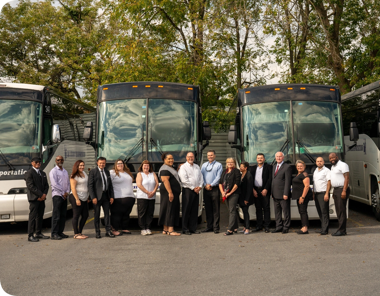 Four charter buses with people standing in front of them